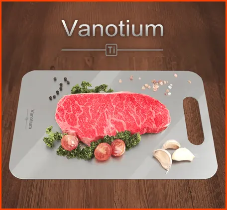Vanotium cutting board holding a steak, herbs, tomatoes and garlic